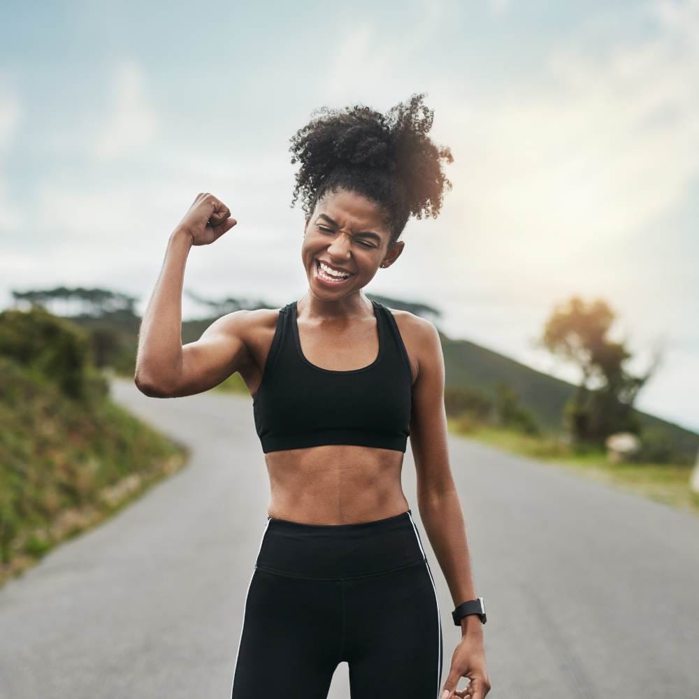 Cropped shot of a young female athlete flexing her bicep outside