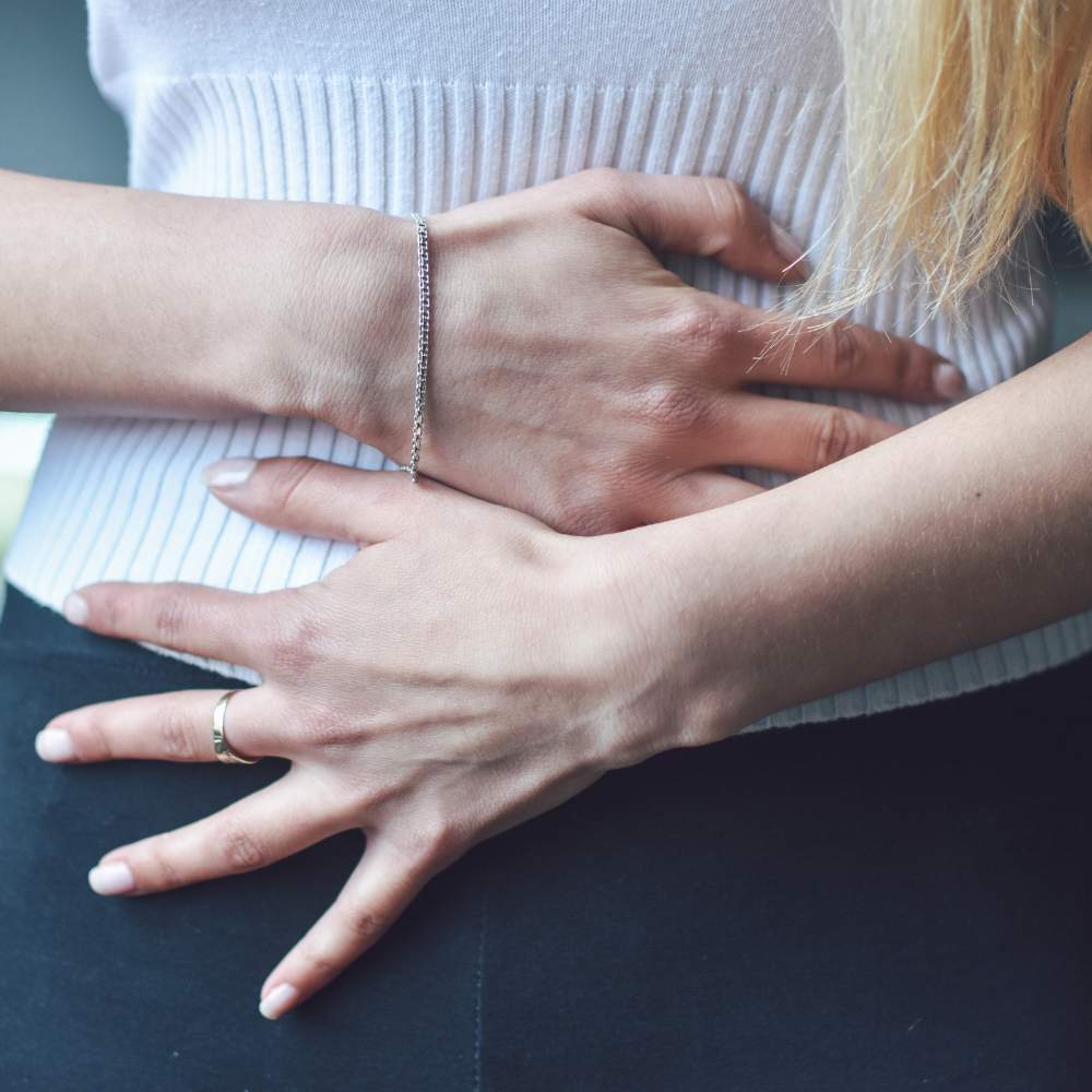 white female with both hands on her lower stomach region