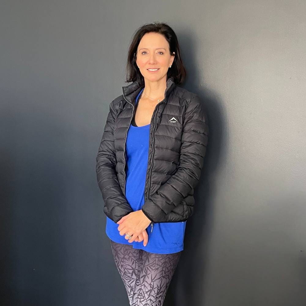 Female BODYTEC member standing infront of the grey wall