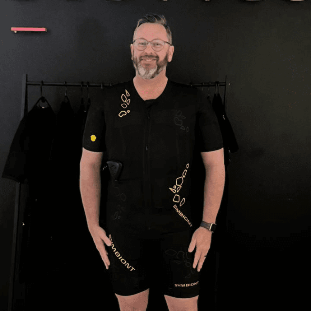 White male BODYTEC member standing in fron of a grey wall
